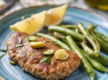 Escalope de veau au citron et fèves vertes servie dans une assiette en grès de couleur bleue